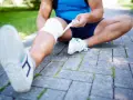 En löpare bandagerar sitt ben, möjligen för att lindra smärta från benhinneinflammation symptom.