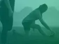 Två personer stretchar utomhus i dimma. En kvinna på knä sträcker sig mot sin fot. Detta kan vara en del av rehab benhinneinflammation.