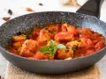 Bocconcini di pollo in padella con pomodoro e basilico, un piatto succulento pronto per essere gustato.
