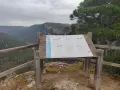 Mirador en el **zaorejas alto tajo**, con panel informativo sobre aves de hoces y cañones. Paisaje de montañas verdes y cielo nublado.