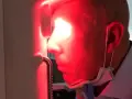 Uomo con maschera chirurgica sotto il mento, riceve fotobiomodulazione facciale. Attenzione alle fotobiomodulazione controindicazioni.