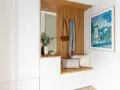 Ideas para decorar recibidor pequeño: banco de madera, espejo, perchero con bolso y bufanda, cuadro y armarios blancos.