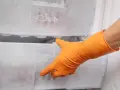 Orange-gloved hand opens a frosty drawer in a freezer. Time to gefrierfach abtauen.