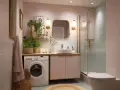 Ein kleines Bad einrichten: Waschmaschine, Waschbecken, Dusche und WC in zarten Rosatönen, mit Pflanzen und goldenen Akzenten.