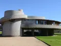 Bâtiment circulaire en béton, exemple des structures conçues par Frank Lloyd Wright, avec des fenêtres rondes et une façade en gradins.