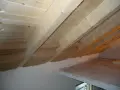 Isolamento tetto dall'interno fai da te: pannelli isolanti in fibra di legno tra le travi di legno grezzo, con sottotetto in perline.