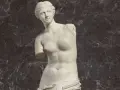 La Vénus de Milo, une sculpture antique en marbre, est représentée ici avec ses bras manquants, posant gracieusement.