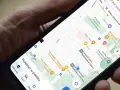 Dłoń trzyma telefon z mapą. Aplikacja do udostępniania lokalizacji pokazuje pobliskie restauracje i sklepy.
