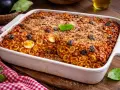 Piatto di anelletti alla siciliana appena sfornato, con uova sode, olive nere e una croccante panatura.