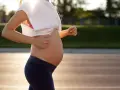 En gravid kvinna springer på en löparbana i solnedgången.