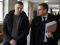 Mężczyzna w czarnej kurtce rozmawia z prawnikiem w todze. Czy usłyszą wyrok w zawieszeniu?