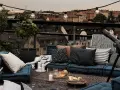 Gemütliche Lounge-Ecke auf einem grossen Balkon mit Blick über die Stadt. Kissen, Decken, Kerzen und ein Teleskop laden zum Entspannen ein.