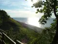 Słoneczny dzień nad morzem, łagodne zbocze porośnięte trawą schodzi do plaży. Jastrzębia Góra atrakcje to spacer po klifie i podziwianie widoków.