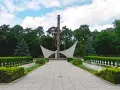 Pomnik i rzędy białych krzyży na cmentarzu w Siekierkach.