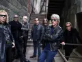 Zespół Bon Jovi gotowy na koncert, w skórzanych kurtkach i okularach przeciwsłonecznych, pozuje na tle industrialnych schodów.