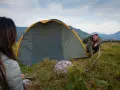 Mann und Frau biwakieren in Deutschland. Sie bauen ein Zelt in den Bergen auf, die Landschaft ist wunderschön.