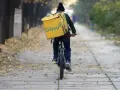 Kurier na rowerze z żółtą torbą Glovo jedzie ależsza. Chyba glovo nie działa, bo wygląda na zagubionego.
