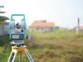 Precyzyjne wznowienie granic działki za pomocą tachimetru. Geodeta przygotowuje teren pod budowę.