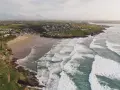 Aerial videography captures a coastal village with a sandy beach and rolling waves.