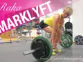 En kvinna utför raka marklyft med en skivstång i ett gym.