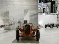 Pomarańczowy Fiat Balilla z 1933 roku na wystawie w Muzeum Fiata w Turynie. W tle inne zabytkowe samochody.