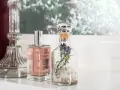 Eleganckie perfumetki męskie w szklanych buteleczkach, jedna z lawendą, obok ozdobnego świecznika.