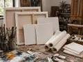 Un atelier d'artiste avec des toiles pour peindre, des pinceaux, des tubes de peinture et une palette.