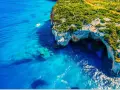 Błękitne morze i klify z jaskiniami to idealne miejsca na Zakynthos, co zobaczyć. Mała łódka kołysze się na falach.