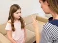Zirytowane dziecko agresywne wobec matki, która grozi palcem. Dziewczynka patrzy w bok z niechęcią.
