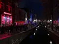 Nocna czerwona ulica Amsterdamu z kanałem i neonami.