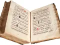 An ancient illuminated manuscript, its pages filled with musical notation and text, evokes the divine hours.
