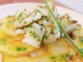 Delicioso plato de sepia al ajillo sobre patatas finas, con perejil picado y un toque de aceite de oliva.