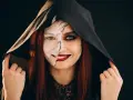 Kobieta w kapturze z połową twarzy pomalowaną na biało, z pęknięciami, druga połowa z ciemnym makijażem. Idealny prosty makijaż na Halloween.
