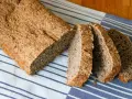 Ein frisch gebackenes vollkornbrot mit hefe, aufgeschnitten auf einem gestreiften Tuch.