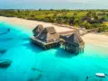 Rajskie plaże i turkusowa woda, idealne tanzania atrakcje. Domki na palach w tropikalnym otoczeniu.