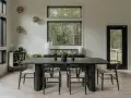 Comedor moderno con mesa negra y sillas de madera. Inspiración para como decorar un comedor grande con vistas al bosque.