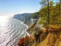 Kreidefelsen an der Ostsee, ein malerischer Anblick, der zu den beliebten Urlaubsorten zählt. Das Meer glitzert, Bäume leuchten in Herbstfarben.