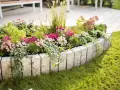 Ein wunderschön bepflanztes Beet mit bunten Blumen und Gräsern, umrandet von Granitsteinen. Perfekt, um neue Ideen für eigene Beet planen zu sammeln.