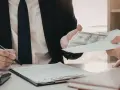 Biznesmen przekazuje kopertę z pieniędzmi, podczas gdy drugi mężczyzna podpisuje dokument. Szybka gotówka windykacja terenowa.