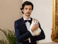 Elegancki mężczyzna w czarny krawat i smoking trzyma białego kota.