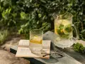 En glasburk med en alkoholfri drink, citron och mynta, står på en bok bredvid ett par glasögon.