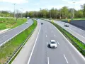Autostrada z kilkoma samochodami i zielonymi pasami.