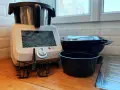 Robot culinaire Monsieur Cuisine Smart prêt à préparer une recette. Accessoires et bols empilés à côté.
