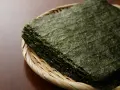 Feuilles d'algue nori empilées dans un panier en osier. Attention, certaines algues peuvent contenir des traces de métaux lourds, un danger potentiel.