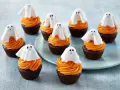 Sju chokladmuffins med orange frosting och vita spökdekorationer. Perfekt att baka till Halloween med barnen!