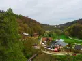 Widok na malowniczą dolinę z zabudowaniami i lasem.