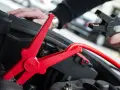 Rotes Kabel mit Krokodilklemme wird an Autobatterie angeschlossen. Plus oder Minus?
