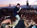 Tłum na Woodstock 99, z wokalistą na scenie i amerykańską flagą. Atmosfera była napięta, co doprowadziło do późniejszych zamieszek i ofiar.