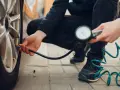 Persona controlla la pressione degli pneumatici dell'auto con un manometro, seguendo la tabella pressione pneumatici auto per la sicurezza.