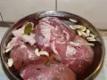 Mięso w misce z wodą, czosnkiem, zielem angielskim i liściem laurowym. To przygotowanie do wędzenia, czyli solanka do wędzenia.